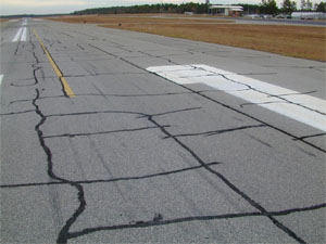 Overview photo of a runway showing block cracking over a large area of the runway surface.            The block cracking is noticeable on the pavement as a pattern of rectangular pieces of pavement where the visible longitudinal and transverse cracks have defined the borders of the           pavement rectangles.  The majority of the cracks in the photo have been sealed.