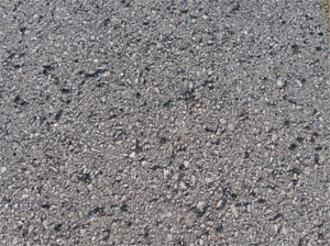 Close-up photo of a small area of asphalt pavement surface with 30 to 40 missing pieces of aggregate.