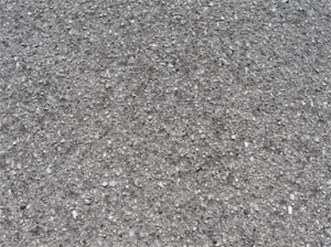 Close-up photo of a small area of asphalt pavement surface with a noticeable loss of coarse aggregate.            The surface is noticeably pitted.