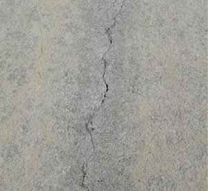 Close-up photo of a single tight crack in a PCC slab.  The crack has no visible spalling.