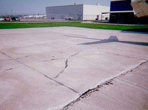 Overview photo showing a slab that is broken into four or five larger pieces.            The cracks that divide the pieces are medium-severity cracks.
