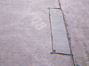 Overview photo of a transverse joint with a small rectangular PCC patch along the joint on one of the slabs.            The patch is in very good condition with no visible signs of distress.