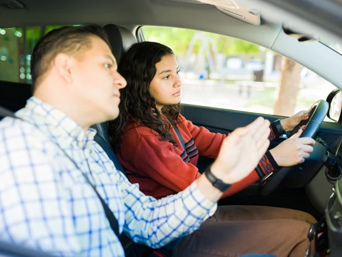 Teen driver taking driving instructions from adult