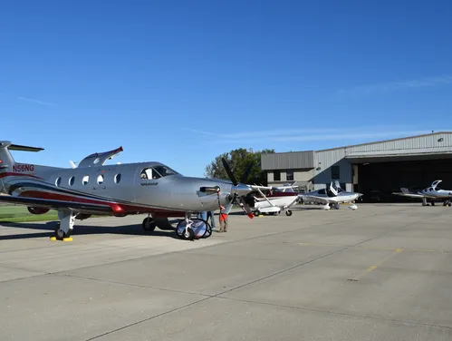 A gray small airplane with red detail sits at an airport