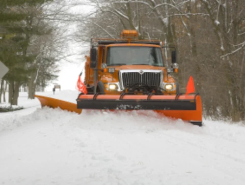 Photo of an orange Iowa DOT Snowplow, plowing snow on a road.