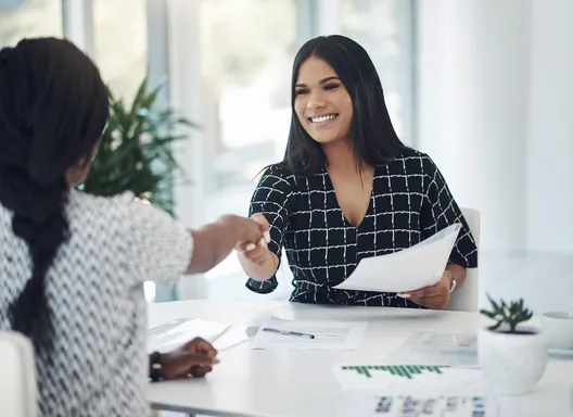 Woman smiling and shaking hands with another woman