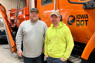 two Iowa DOT employees standing in front of an orange snowplow