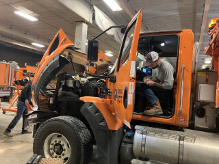 An person sitting in a truck, inspecting it closely