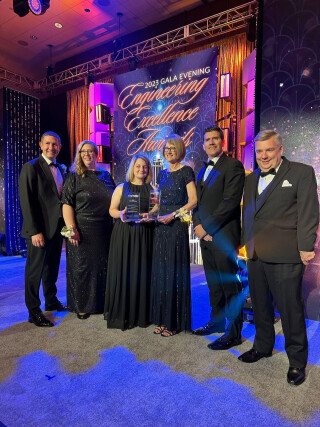 Six people standing to accept an award at a ceremony