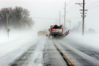 the back of a snowplow truck pushing snow on a winter road