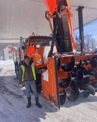 photo of Iowa DOT driver Jeff Nielsen standing in front of a large truck-mounted snow blower
