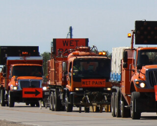 multiple vehicles in a row in the process of painting new lines on a highway