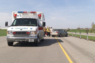 An ambulance with a car on the side of the road