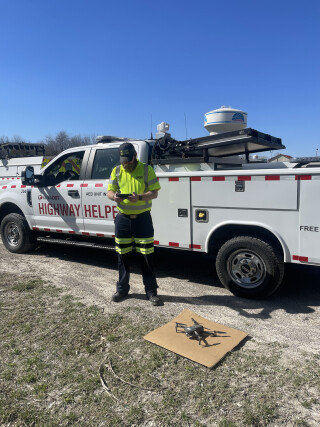 A person next to a work truck, preparing to launch a drone