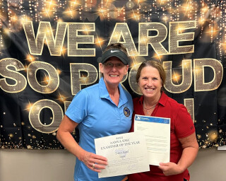 Two people standing together holding awards