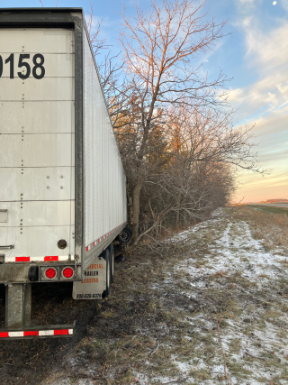 a semi trailer in the woods at the side of a road