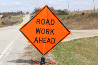 bright orange road sign with the text Road Work Ahead