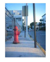 Photo of a sidewalk where a protruding object blocks the pedestrian path, creating an inconsistent and unsafe access route.